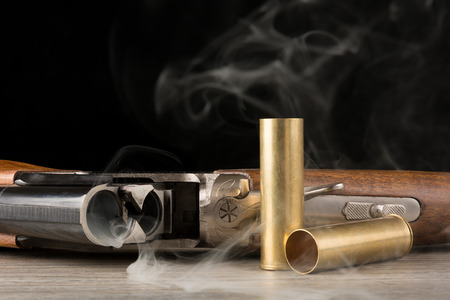Open smoking rifle and two metallic shells. On black background