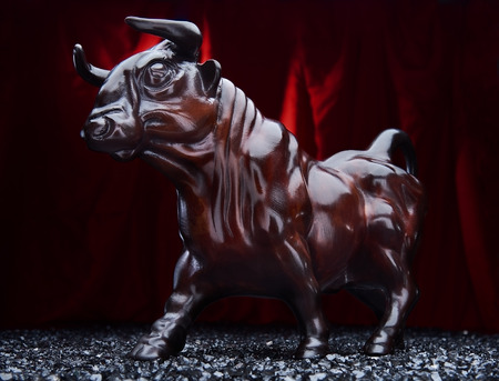 Glossy bull statuette on red rag background. Bullfighting symbolの写真素材