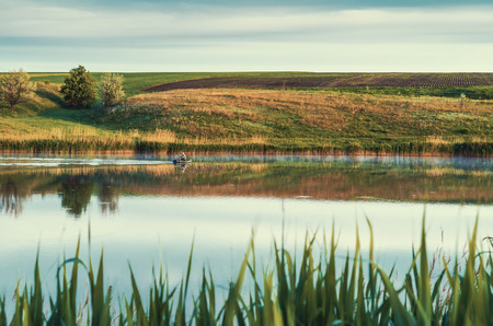 Rural landscape with lake and fishermanの写真素材