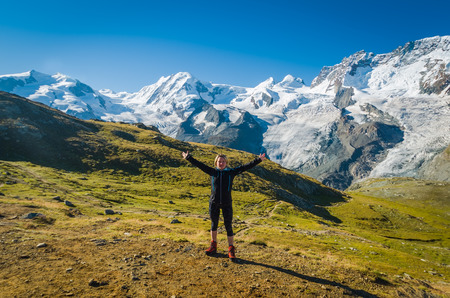 Woman with arms wide open standing in front of Monte rosa glacierの写真素材