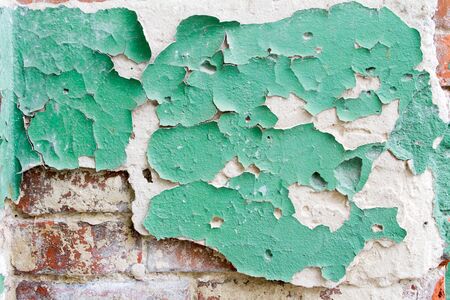 Vintage background texture of old brick masonry on ancient cement with cracks with traces of old paint.の写真素材