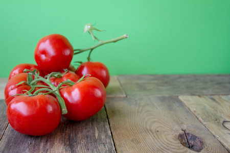 Red cherry tomatoes on a wooden table on a background of a green wallの写真素材