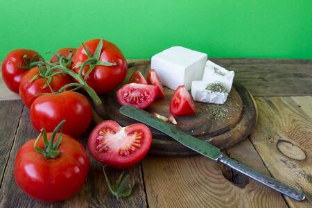 Red cherry tomatoes on a wooden table on a background of a green wallの写真素材