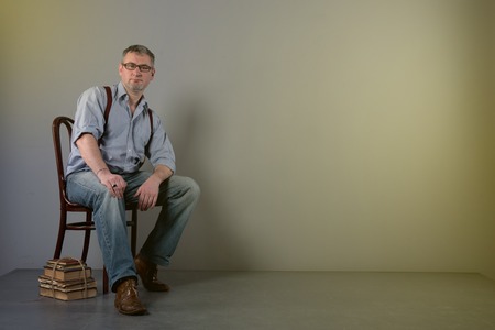 Writer with glasses and suspenders is thinking about his workの写真素材