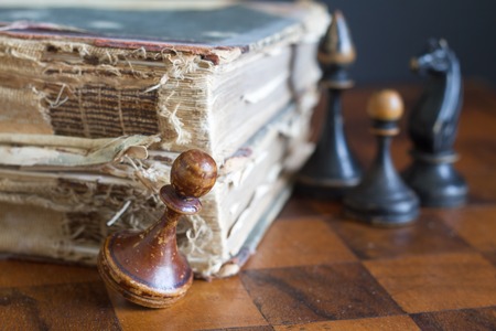 Vintage wooden chess pieces on an old chessboard.