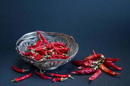 Red Chili pepper in a silver vase on a black background