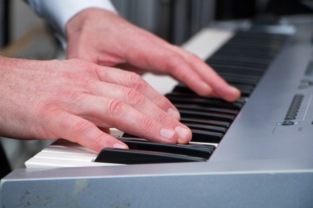 Beautiful man's hands on the keys of synthesizer, selected focus.
