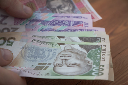 Ukrainian national currency, bills of different values, the calculation between people, the transfer of money, wood background.の写真素材