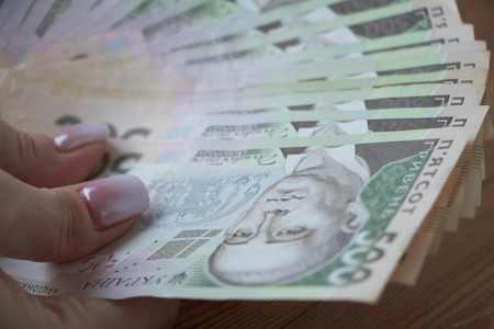 Ukrainian national currency, bills of different values, the calculation between people, the transfer of money, wood background.の写真素材