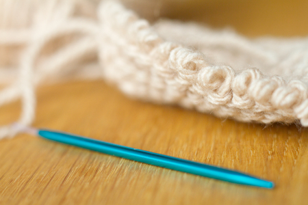 Extremely close-up knitting from beige yarn, needle, crochet hooks. Work on a new product. Selective soft focus. Free space for text.の写真素材