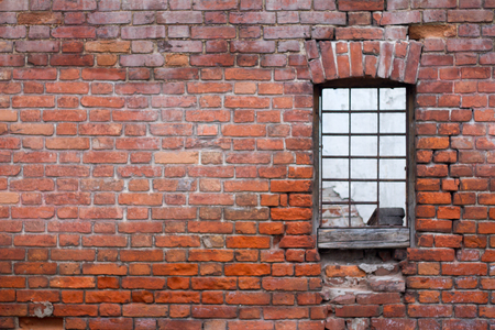 Window with bars on the background of the brick wall of the old house, free space for text