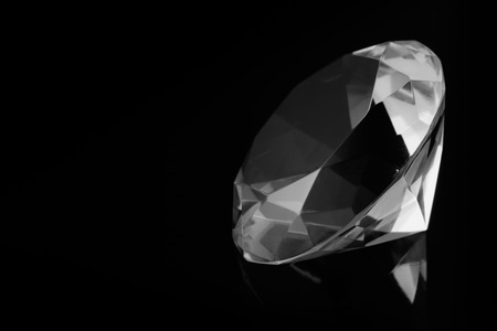 A huge diamond on a black mirror surface with a reflection of a diamond, black and white photo, free space for text.の写真素材