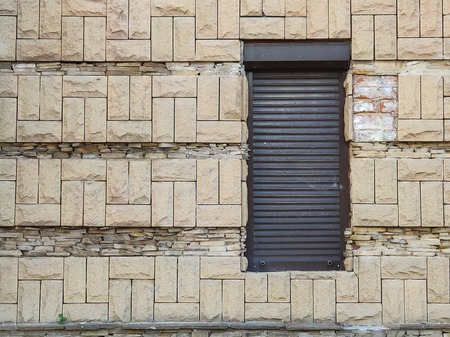 Black roll-metal door against old light brick wall, passage to the store or theater, rear exit, free space for textの写真素材