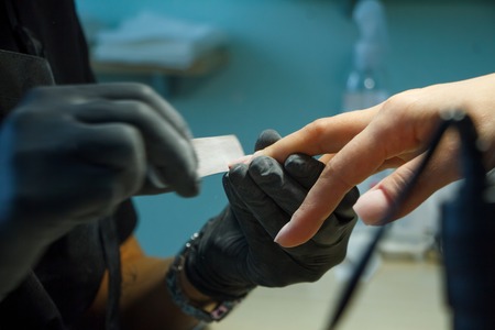 Beautician grinds the nail bar for a manicure in the beauty salon. Finger nail treatment, grinding and polishing. Manicurist Hands Make Female manicure in the nail Salon.の写真素材
