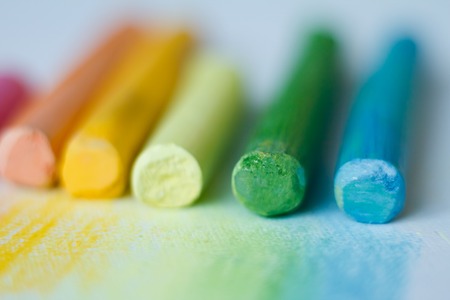 Extreme close-up of multicolored pastel chalks on a white surface, selective focus