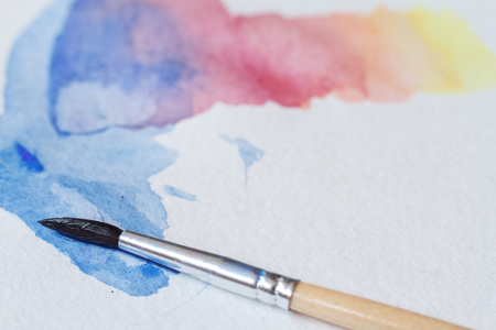 Close-up of beautiful watercolor brushstrokes on a white sheet, a brush in the picture, background or conceptの写真素材