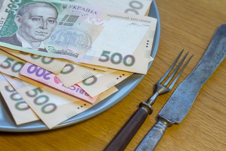 Closeup of Ukrainian money lying on a plate with a fork and knife, business conceptの写真素材