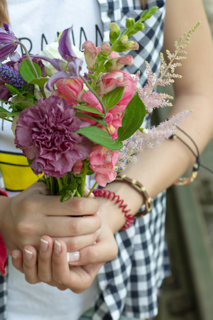 Closeup of girl's hands holding a bouquet of wildflowers, selective focus.の写真素材