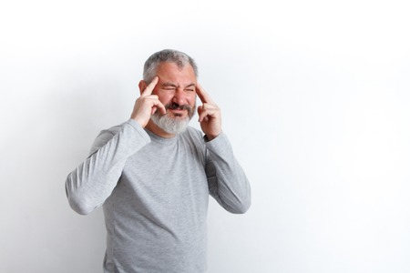 Gray-haired man with a beard suffering from headache desperate and stressed because pain and...