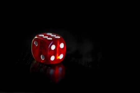 Closeup of a red dice with a winning number on the top face on a black mirror surface, winning conceptの写真素材