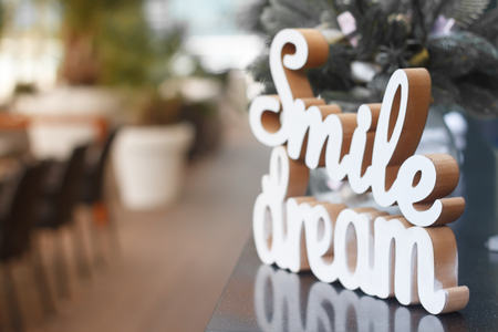 Closeup of smile and dream wooden words on a glass surface over the festive table, selective focusの写真素材