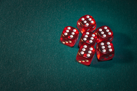 Close-up of several red dice with different digital combinations on green cloth in a casino, concept...