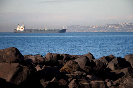 View of the huge sea liner from the rocky shore against the blue sky, copyspaceの写真素材