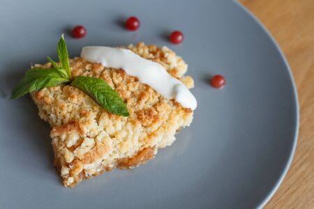 Served slice of freshly baked homemade apple crisp pie with cream and berries on a gray plateの写真素材
