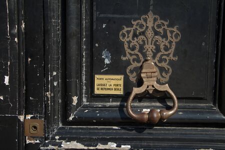 Paris, France - July 05, 2018: Close-up vintage black door with a copper handle beater and a sign with the address and name of the tenant on Place Vendomeのeditorial素材