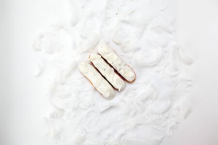 A set of three eclairs with white chocolate decor isolate on a white surface decorated with white...