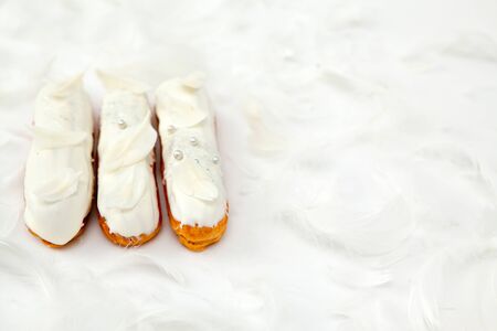 A set of three eclairs with white chocolate decor isolate on a white surface decorated with white...