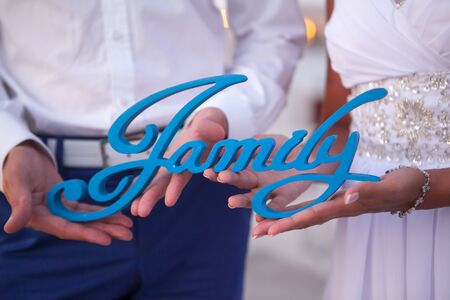 Close-up of the hand of a man and a woman holding the wooden word Familyの写真素材