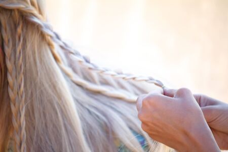 Closeup female graceful hands tangle blond hair in small pigtailsの写真素材