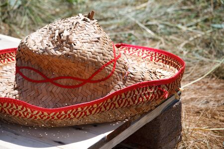 An old holey mens straw hat with red embroidery on a blurred natural background, selective focusの写真素材