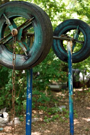 Closeup of a rough home-made simulator from old tires among thick trees in a city park, healthy...