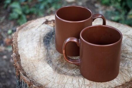 Closeup of two brown clay empty cups on a wooden stumpの写真素材
