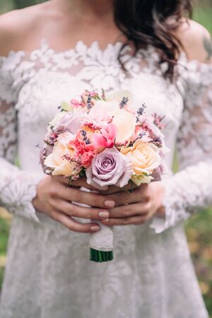 Closeup bridal bouquet of spring pink and white flowers on a blurred background, selective focus