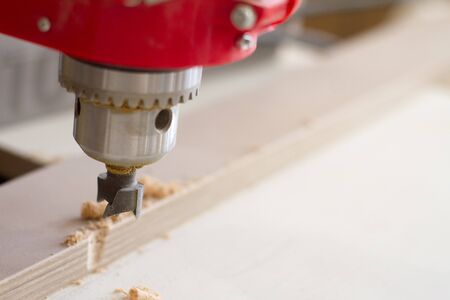 Close-up of the head of the drilling machine with nozzle in the furniture workshop, selective focus