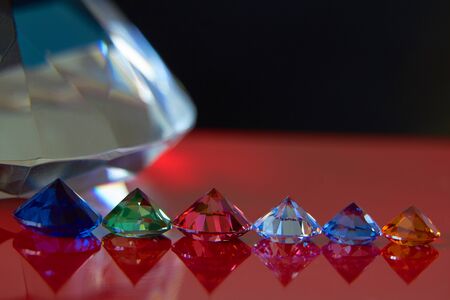 Huge diamond and several chic crystals on a red and black surface, shimmer and sparkle, free space for text.の写真素材