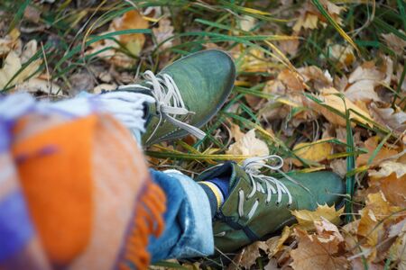 Close up of a leg in green hiking boots with laces in the autumn forest against a background of yellow fallen foliage, selective focusの写真素材