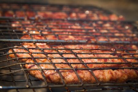 Close up of sausages fried on a roasting pan over a bonfire, a golden crust from the grill, selective focusの写真素材