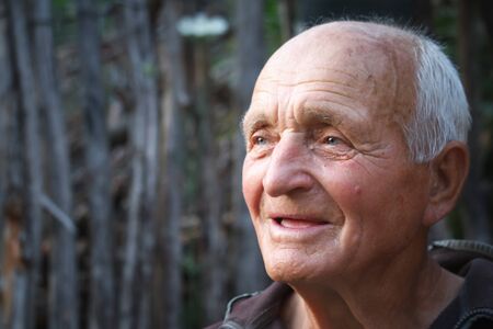 Closeup portrait of a very old man against the background of wattle, selective focusの写真素材