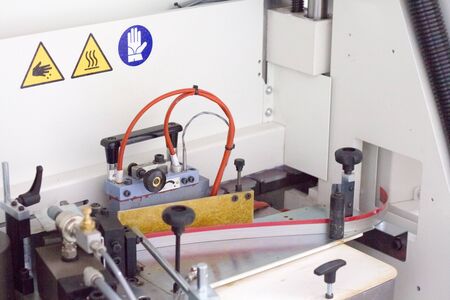Close up mechanism of single sided automatic edge banders in a private furniture workshop, selective...