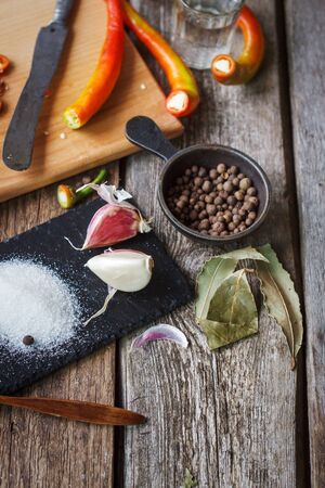 Close up of chopped hot chili peppers and heaps of salt, sugar, garlic, allspice, bay leaf on an old wooden surface, selective focusの写真素材