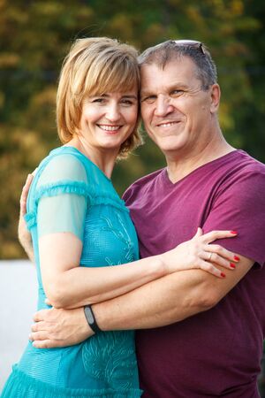 Middle-aged couple smiling and hugging on city street, selective focus