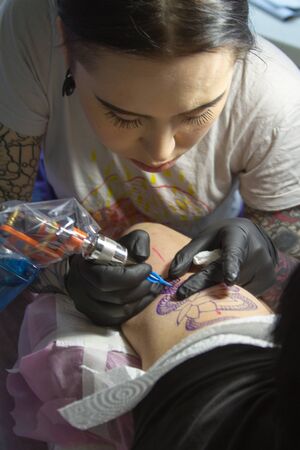 Kharkiv, Ukraine - April 08, 2017: Young professional tattoo artist makes a tattoo on the arm of clientのeditorial素材
