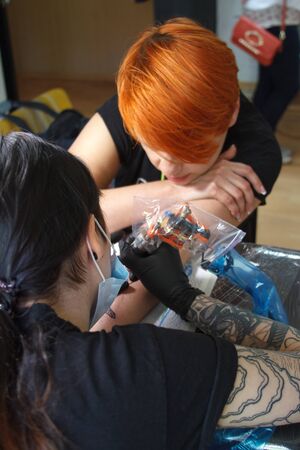 Kharkiv, Ukraine - June 4, 2017: Young professional tattoo artist makes a tattoo on the arm of clientのeditorial素材