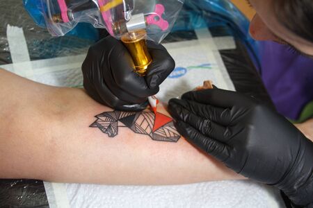 Kharkiv, Ukraine - June 4, 2017: Close-up of the hand of a tattoo master in black gloves with a...