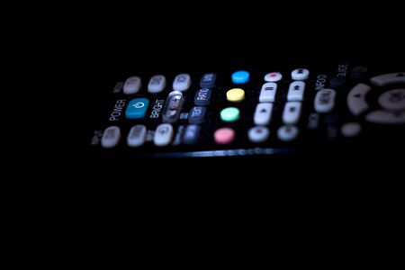 Close up of a television remote control glows in the dark, selective focusの写真素材