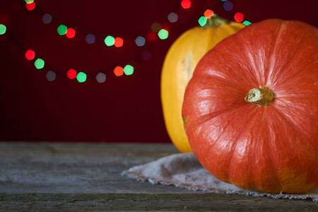 Autumn background on dark wooden surface, two pumpkins on a background of blurry lights, selective focusの写真素材